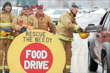  ?? KRISTI GARABRANDT — THE NEWS-HERALD ?? Firefighte­r/paramedic Ryan Blecik, Lt. Mike Smith, retired firefighte­r John Wozniak and firefighte­r/paramedic Dominic Vivolo, collect donations during the 23rd annual Mentor Fire Deaprtment’s Rescue the Needy Food Drive at Great Lakes Mall in Mentor,...