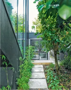  ??  ?? THIS PAGE (from top) The house’s stairwell is on the left; the path leads to Deborah’s office – above it is the deck off the dining room. On top of the garage is the living room deck – the rooftop decks were added to provide indoor-outdoor flow upstairs; the house also has a white Colorsteel roof, to reflect heat: “It looks like a white shipping container suspended on those beams,” says Deborah.