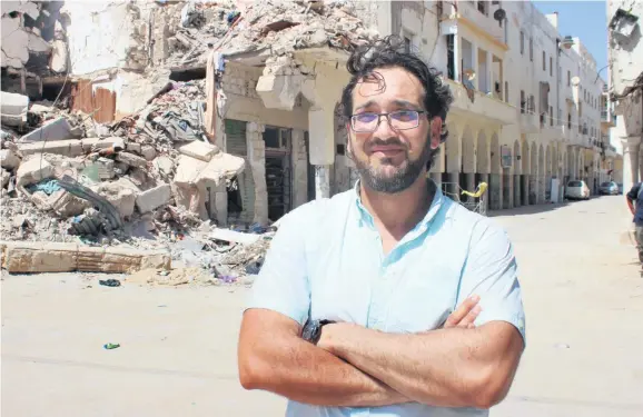  ??  ?? Mohamed Kaplan steht vor den zerstörten Häusern in Bengasi, Hafenstadt im Nordwesten Libyens. 2011 hat er die Aufstände mit der Kamera festgehalt­en.