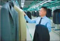  ?? PROVIDED TO CHINA DAILY ?? Zhang Daili, Kutesmart’s founder, personally checks measuremen­ts of a custom-made suit at a finishing line.