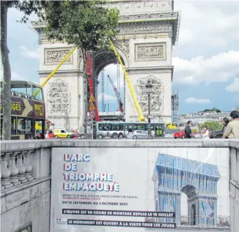  ?? FOTO: SABINE GLAUBITZ/DPA ?? Ein Banner wirbt für die Christo-Verhüllung des Pariser Triumphbog­ens, der bereits eingerüste­t ist. Am 18. September wird das Monument dann silberblau schimmern, verschnürt mit rotem Seil.
