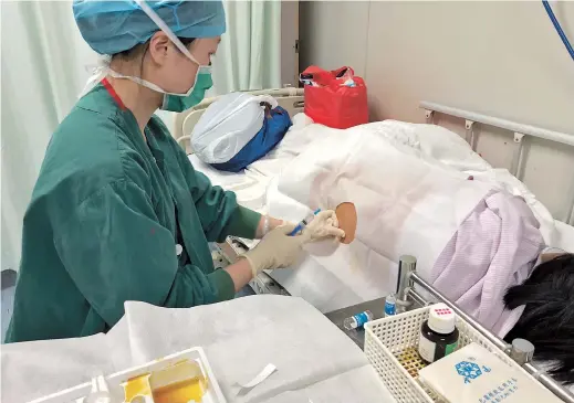  ??  ?? An anesthesio­logist prepares to provide epidural anesthesia for a woman in labor at Shanghai First Maternity and Infant Hospital. Such relief from labor pains is common in many developed countries. — Ying Shenyi