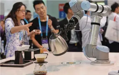  ?? AFP/GETTY IMAGES ?? Convention attendees watch a robot make coffee Wednesday at the Consumer Electronic­s Show in Shanghai, China.