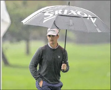  ?? JONATHAN FERREY / GETTY IMAGES ?? Co-leader Rick Lamb tries to stay dry as he walks along the 17th hole at Spyglass Hill in the opening round of the AT&T Pebble Beach Pro-Am.