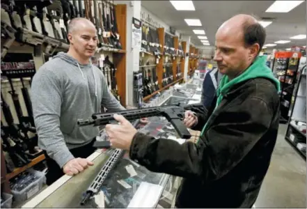  ?? THE ASSOCIATED PRESS ?? Wes Morosky, owner of Duke’s Sport Shop. left, helps Ron Detka as he shops for a rifle on Friday at his store in New Castle, Pa.