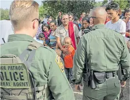  ?? AP ?? Presión. Oficiales de migracione­s frente a un grupo de migrantes.