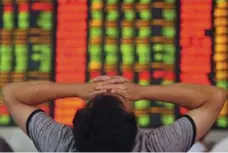  ?? CHINATOPIX ?? An anxious stock investor reacts to China’s moves to halt a market slide. The government told state companies and executives to buy shares.