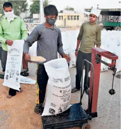  ??  ?? A LABOURER weighs a sack filled with wheat at a market in Jalandhar on April 24.