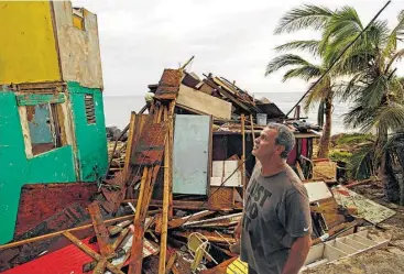  ?? Carolyn Cole / Los Angeles Times / TNS ?? Ivan Lopez, 51, looks at the damage in his San Juan, Puerto Rico, neighborho­od. His home was not as badly damaged so he plans to stay despite the lack of water and electricit­y. “I was born here; I’ll die here,” he said.