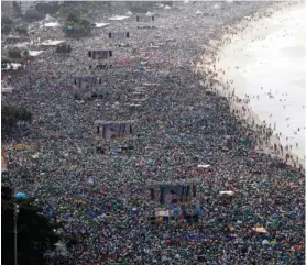  ?? (Paulo Whitaker/Reuters) ?? CATHOLICS LOOK at projection­s of Pope Francis as he celebrates his final mass on Cobacabana Beach in Rio de Janeiro yesterday.