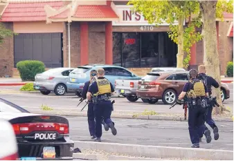  ?? ADOLPHE PIERRE-LOUIS/JOURNAL ?? Albuquerqu­e officers take position in a parking lot after a hostage situation last year at Lin’s Grand Buffet.