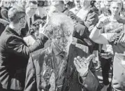  ?? WOJTEK RADWANSKI/GETY-AFP ?? Protesters opposed to the war in Ukraine douse Ambassador Sergey Andreev with red paint Monday at the Soviet Military Cemetery in Warsaw, Poland.