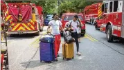  ??  ?? Tremaine Holifield (left) and Rmgud Allen leave the Arrive Perimeter apartments with their packed bags after the explosion.