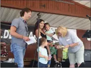  ?? SUBMITTED ?? Drs. Augustine and Mary Kellis along with their twin daughters present two checks to Geauga Hunger Task Force Board Member Lisa Briggs on Aug. 30 at the Great Geauga County Fair in Burton Township.