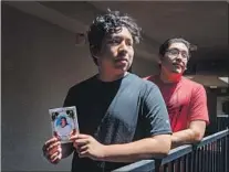  ??  ?? SEAN SOLIS, 15, left, holds a funeral card of his grandmothe­r, Isabel Lainez, who died in 2016 while waiting for a specialist appointmen­t. With Solis is his 21-year-old brother, Steven.