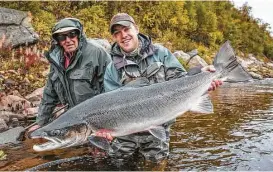  ?? Ollie Thompson ?? An angler, flanked by his guide, holds up his catch before releasing it back into the river. The fish are carefully noted and tagged before their release so that scientists can monitor the health of the salmon population. Boats depart the Ryabaga Camp...