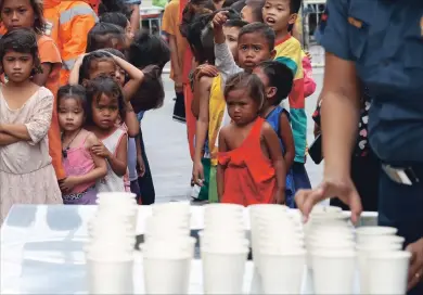  ?? BULLIT MARQUEZ THE ASSOCIATED PRESS ?? Children living in the Philippine­s coastal community of Baseco wait to receive rice porridge as they seek temporary shelter at an evacuation centre.