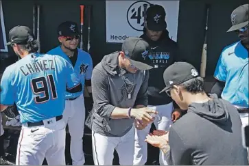  ?? Michael Reaves Getty Images ?? MIGUEL ROJAS of the Miami Marlins gives teammate Jordan Yamamoto sanitizer after shaking his hand before a Grapefruit League spring training game against the New York Yankees in Jupiter, Fla.