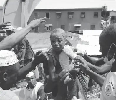  ?? SUNDAY ALAMBA / THE ASSOCIATED PRESS ?? A child is pulled from the rubble of a collapsed building in Lagos on Wednesday which housed a school with up to 100 children inside. The three-storey school building collapsed while classes were in session.