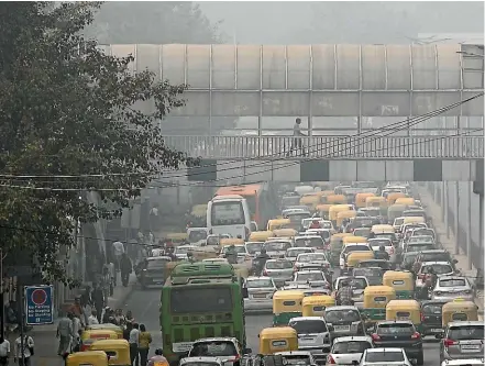  ?? AP ?? A pedestrian walks on a bridge above vehicle traffic in New Delhi in November 2019 as the city is enveloped under thick smog. The air quality index exceeded 400, about eight times the recommende­d maximum. A study released yesterday blames pollution of all types for 9 million deaths a year globally, with the death toll attributed to dirty air from cars, trucks and industry rising 55% since 2000.