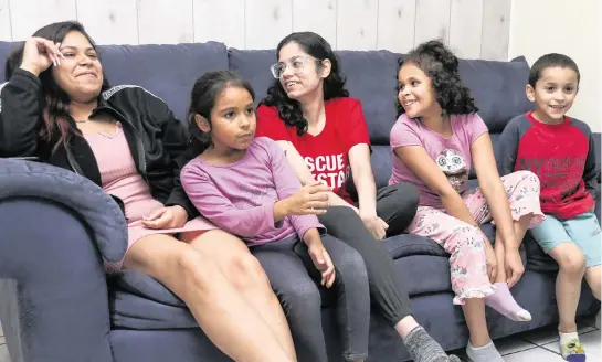  ?? SAM NAVARRO Special for the Miami Herald ?? Jasmine Santana, 22, left, tells a story as her younger siblings Janabella, 7, Janelly, 18, Jaseline, 8, and Janthony, 6, react to the story while listening from the leaving room couch at their home in North Miami, Florida on Tuesday, December 6, 2022.