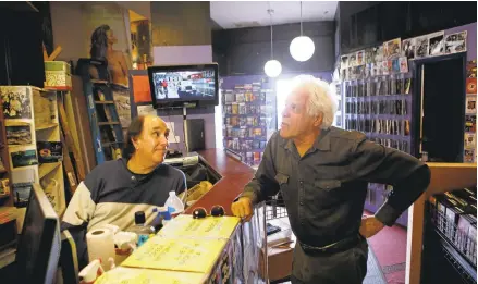  ?? JIM GENSHEIMER/STAFF ?? Ira Belfer, left, owner of Captain Video in San Mateo, discusses movie options Friday with customer Robert Caughlan, of San Mateo. Belfer’s extreme dedication and customer service have kept the store running. Below, An old VHS case sports the store...