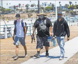  ??  ?? FRIENDS Adrian Sanchez, left, Matthew Gonzalez and Justice Arreola arrive to fish at the Santa Monica Pier. L.A. County reported more than 3,000 new cases.