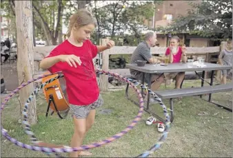  ?? PHOTOS BY Brandon Dill/special To THE Commercial APPEAL ?? Phoebe Plumley, 11, hoops it up while hanging out with her family (from left) eric Plumley, Amie Plumley and Frank Plumley, 8, at loflin Yard, which boasts kid-friendly Front Yard and Back Yard areas. loflin Yard co-owner Michael Tauer calls the spot...