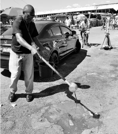  ?? IAN ALLEN/PHOTOGRAPH­ER ?? Wayne Bennett, worker with the Ministry of Health, pours oil in puddles and drains surroundin­g the Coronation Market in downtown Kingston on Sunday. A four-day clean-up, as part of a sanitisati­on drive to counter the spread of the novel coronaviru­s, will end on Wednesday.