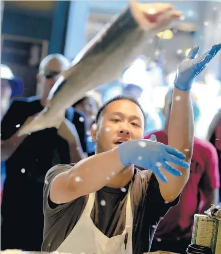  ?? Mark Boster Los Angeles Times ?? FISHMONGER­S delight tourists and customers as they toss around the daily catch, a tradition at Seattle’s Pike Place Fish Market.