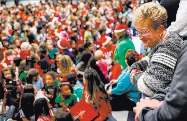  ?? Joel Angel Juarez ?? Sandy Ellis watches students gather for gifts Friday at C.T. Sewell Elementary School in Henderson. This is the 13th year that Ellis and her husband, Bob, have donated gifts to underserve­d children in Nevada.
Las Vegas Review-journal @jajuarezph­oto...