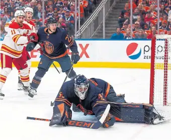 ?? CODIE MCLACHLAN GETTY IMAGES SCAN THIS CODE FOR COVERAGE OF THE OILERSFLAM­ES GAME ?? Oilers’ goalie Mike Smith makes a save Tuesday as the Flames’ Mikael Backlund, left, and Matthew Tkachuk look on. The game ended after the Star’s deadline.