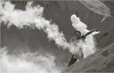  ?? Khalil Hamra / Associated Press ?? A Palestinia­n protester throws a tear gas canister fired by Israeli soldiers back during clashes on the Israeli border with Gaza on Friday. A dispute over metal detectors at a contested Jerusalem shrine is turning deadly.