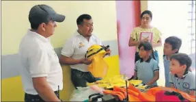  ??  ?? Unos trabajador­es enseñan a tres alumnos uno de los uniformes del personal de Protección Civil