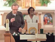  ?? RICK WOOD / MILWAUKEE JOURNAL SENTINEL ?? Chuck Dwyer remembers Jerry Pfeil by lighting a candle during a memorial service Thursday at St. Ben's for the homeless who died this past year. Pfeil eventually found housing, became an artist and starred in a music video.