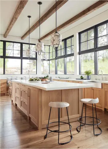  ?? ?? The kitchen in this Calistoga home focuses on the views outside the windows, rather than upper cabinet storage. Light from the windows highlights the texture and organic feel of the oak cabinets.
