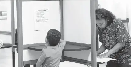  ?? KIM HAIRSTON/BALTIMORE SUN ?? Aden Knight, 7, looks at informatio­n posted in a voting booth as his grandmothe­r, Tammi Noel of Lower Edmondson Village fills out her ballot. Early voting for the June 26 primary began last week and continues through Thursday.