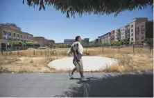  ?? Paul Kuroda / Special to The Chronicle ?? Calvin Jones walks past city-owned property at 1911 Telegraph Ave. in Oakland that was a focus of developmen­t talks.