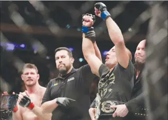  ?? AP PHOTO ?? Georges St. Pierre celebrates after defeating Michael Bisping, left, in a middleweig­ht title mixed martial arts bout at UFC 217 in New York.