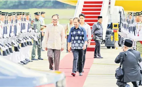  ?? — Bernama photo ?? Anwar (le ) accompanie­s Sultan Hassanal on the red carpet following His Majesty’s arrival at the RMAF base. Seen behind the Sultan is Pengiran Muda ‘Abdul Mateen.