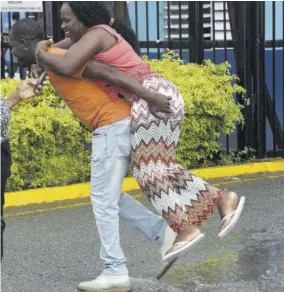  ??  ?? A woman is assisted over puddles as it begins to rain outside the National Arena at the 80th annual conference of the People’s National Party yesterday.