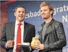  ?? FOTO: AFP ?? Wiesbadene­r Weltmeiste­r-Wegzehrung: Nico Rosberg (re.) und der Oberbürger­meister der hessischen Landeshaup­tstadt, Sven Gerich (SPD), mit einem Krug Äppelwoi und einem Teller „Handkäs mit Musik“.