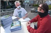  ?? Dan Watson/The Signal ?? Author Stephen Tako, left, autographs a copy of his new book, “Junga the Dancing Yeti meets Heidi” for Tom Smalley during a book-signing event held at Rustic Berger House in Santa Clarita recently.