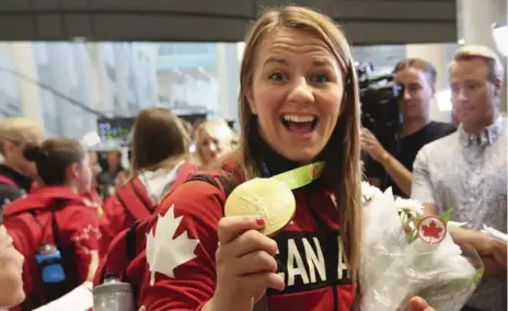  ?? RICHARD LAUTENS PHOTOS/TORONTO STAR ?? Gold medal wrestler, Erica Wiebe, shows off her hardware as she is greeted by media and fans at Pearson airport.