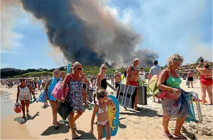  ?? PHOTO: REUTERS ?? Tourists evacuate the beach as smoke fills the sky above a burning hillside in Bormes-les-mimosas, in the Var department of Provence, France.