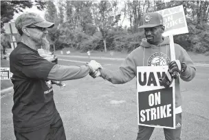  ?? MATT ROURKE/ASSOCIATED PRESS ?? Picketers Richard Rivera, left, and Will Myatt react Wednesday to news of a tentative contract agreement with General Motors, in Langhorne, Pa. Bargainers for General Motors and the United Auto Workers reached a tentative contract deal Wednesday that could end a monthlong strike that brought the company’s U.S. factories to a standstill.