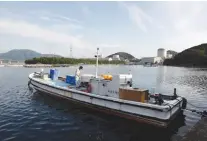  ?? (Reuters) ?? A BOAT IS seen at a fishing port in western Japan as Kansai Electric Power Co.’s Mihama nuclear power plant is pictured in the background.