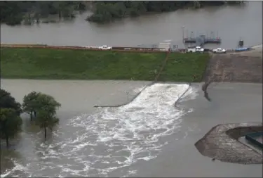  ?? BRETT COOMER — HOUSTON CHRONICLE VIA AP ?? In this aerial photo, water is released from the Addicks Reservoir as floodwater­s rise from Tropical Storm Harvey on Tuesday in Houston.