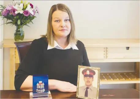  ??  ?? Tricia Kirkwood shows her father’s photo and police badge. Ottawa Police Const. David Kirkwood was shot and killed in the line of duty on July 11, 1977.