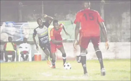  ??  ?? Dwayne Charles (centre) of the Guyana Police Force (GPF) trying to evade his Mahaica Determinat­ors marker during their 2-2 stalemate at the GFC ground in the Petra Organizati­on/Limacol Football Championsh­ip